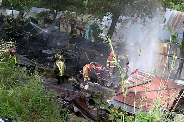 Bomberos revisan escombros de vivienda incendiada. (Foto Prensa Libre: Erick Ávila)