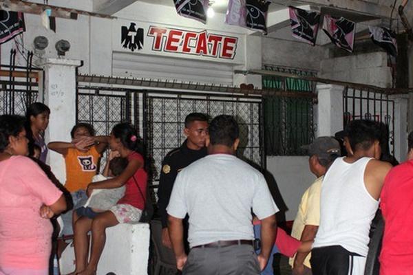Vecinos se reúnen frente al negocio donde murió baleada Guadalupe Díaz Ralda, en Puerto Barrios. (Foto Prensa Libre: Edwin Perdomo)