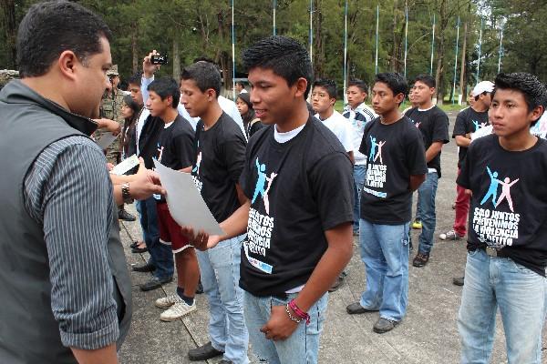 Adolescentes reciben diploma de participación en campamento.