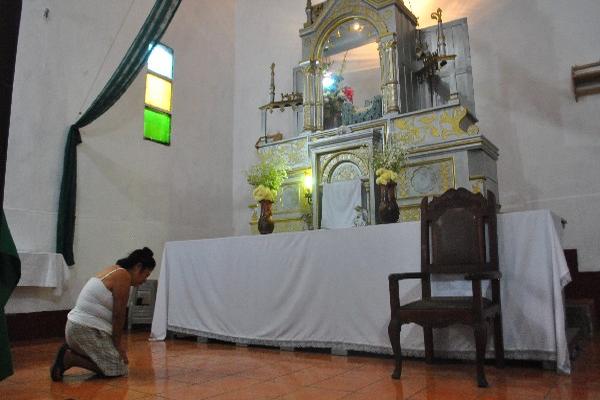 Una mujer reza frente al altar  donde se encontraba la imagen del Niño de Atocha, la cual fue sustraída, en Santa Cruz Muluá, Retalhuleu.