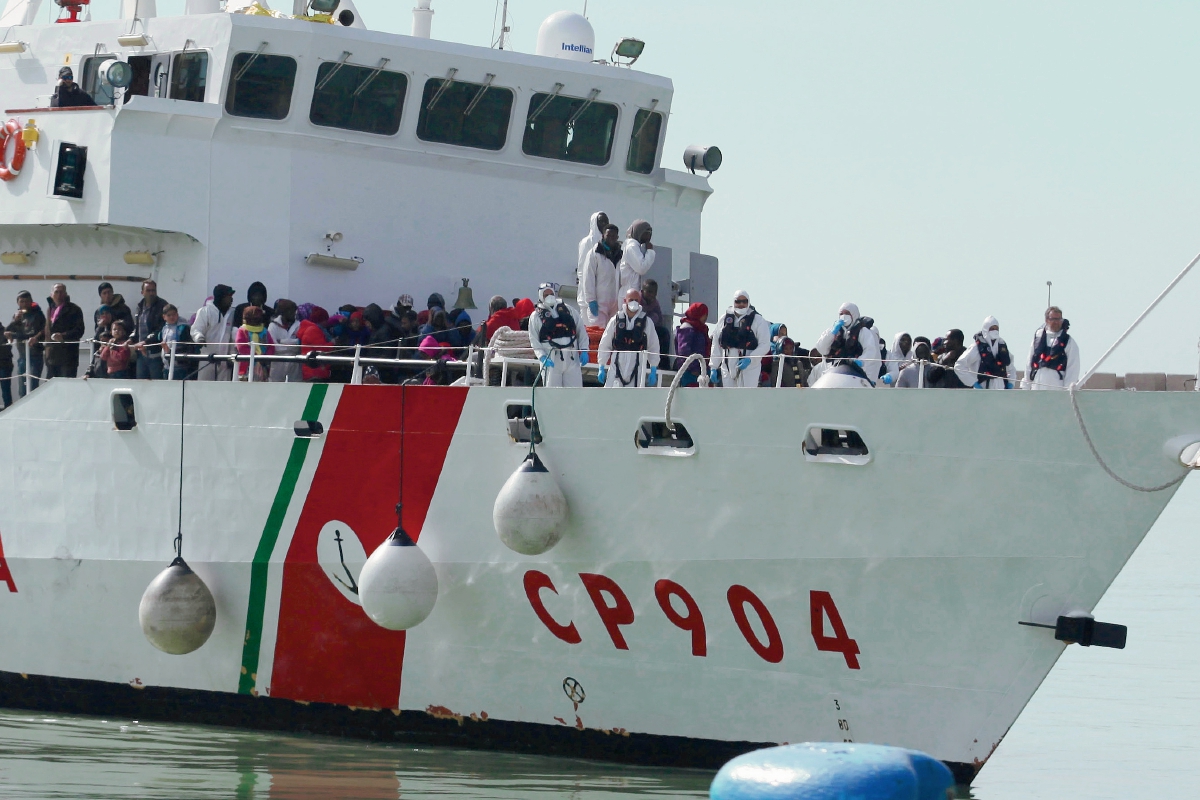 Inmigrantes rescatados esperan desembarcar de un buque de la Guardia Costera italiana. (Foto Prensa Libre:AP
