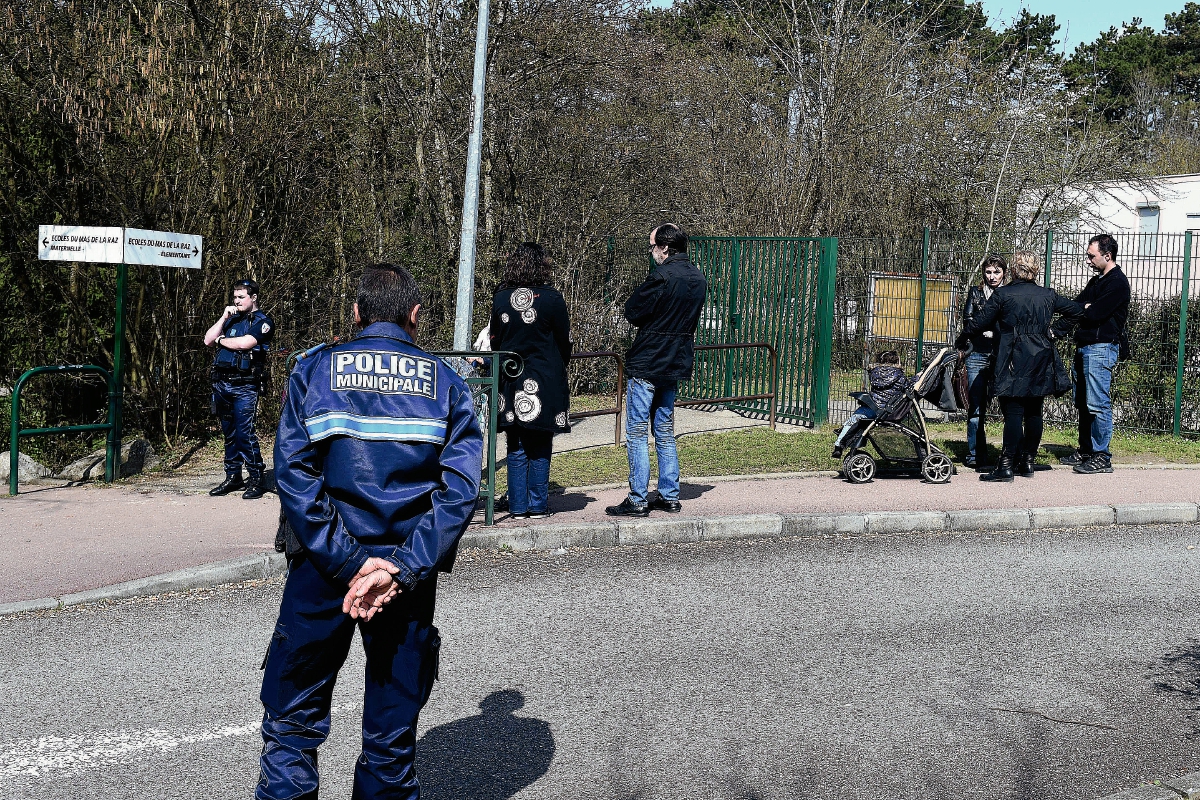 Oficiales de la Policía francesa vigilan el exterior de la escuela primaria "Le Mas de la Raz", cuyo director fue arrestado por abuso a menores. (Foto Prensa Libre: AFP).