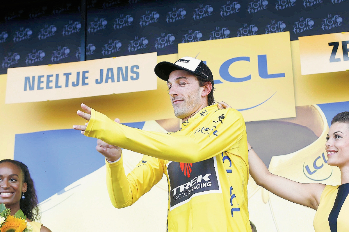 Las edecanes ayudan a Fabian Cancellara a colocarse el suéter de líder del tour. (Foto Prensa Libre: EFE)