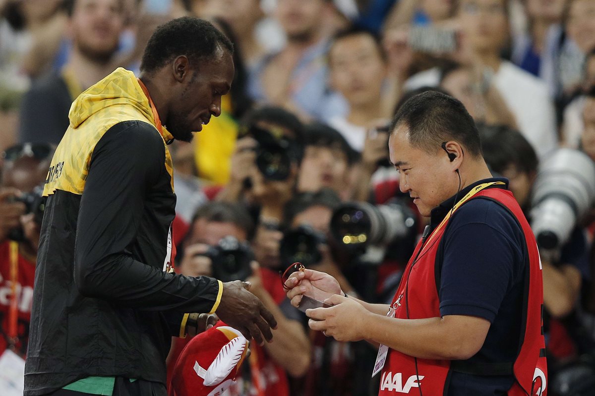 Usain Bolt recibe la pulsera que le regaló Tao Song, tras el incidente de ayer. (Foto Prensa Libre: AFP)