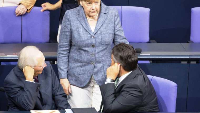 Angela Merkel conversa con los ministros de Finanzas, Wolfgang Schäuble (izq), y de Economía, Sigmar Gabriel, durante el debate y votación del tercer rescate a Grecia