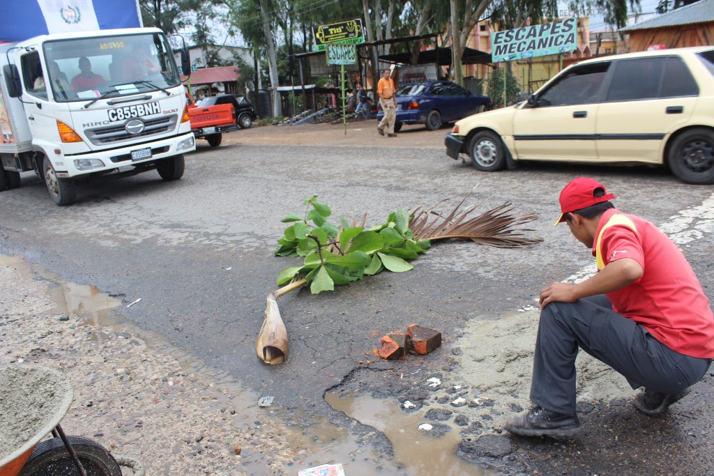 Empleado de una gasolinera hecha cemento en un bache en el km 116.5 de la ruta Interamericana, en Jutiapa. (Foto Prensa Libre: Óscar González)