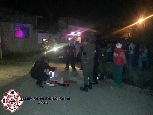 Un agente de la Policía cubre el cadáver del fallecido en la colonia San José. (Foto Prensa Libre: Asonbomd)