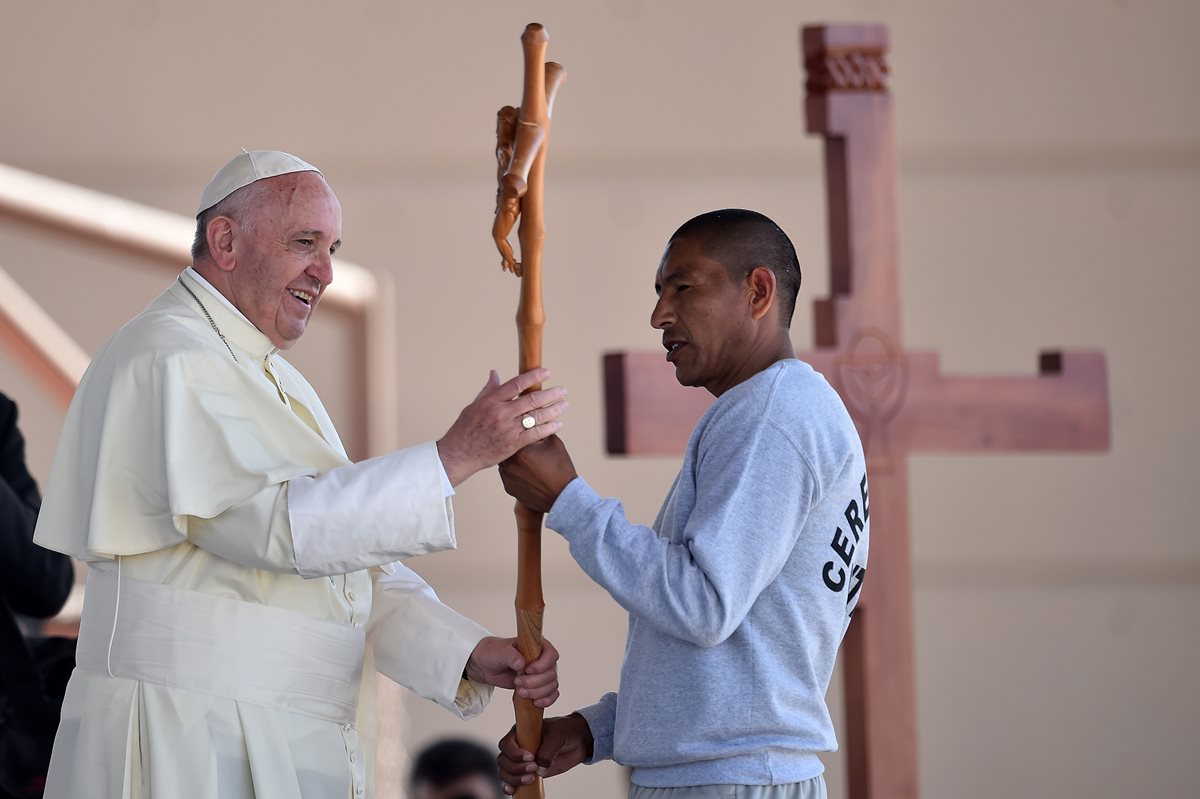 El papa Francisco recibe un crucifico de un reo durante la visita que hizo al penal de Ciudad Juárez. (Foto Prensa Libre: AFP).
