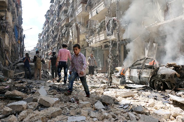 Sirios <span>caminan</span> <span>en medio de</span> <span>los escombros de</span> <span>edificios destruidos</span> por <span>un</span> <span>ataque aéreo. (AFP).</span>