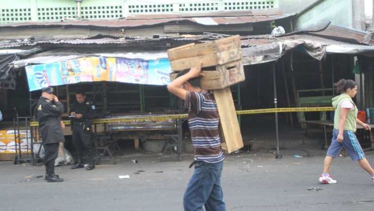 Vendedores comienzan a laborar mientras la PNC resguarda el lugar donde se localizó el cadáver. (Foto Prensa Libre: Érick Avila)