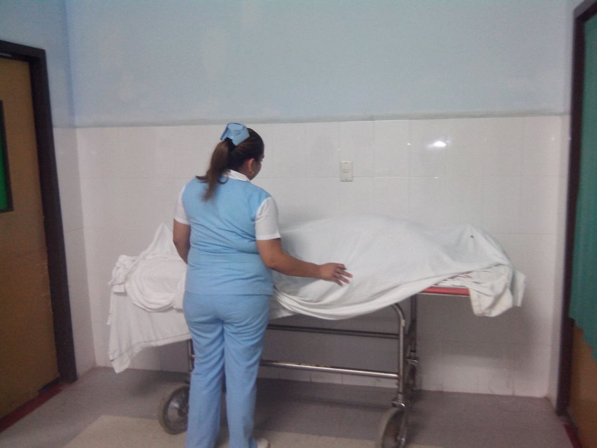 Enfermera cubre con una sábana el cuerpo sin vida de Héctor Leiva López. (Foto Prensa Libre: Hugo Oliva)