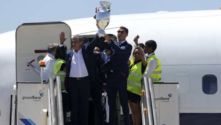 La estrella portuguesa Cristiano Ronaldo levanta el trofeo de la Eurocopa antes de abordar el vuelo que trasladó a la selección a territorio luso. (Foto Prensa Libre: AFP)