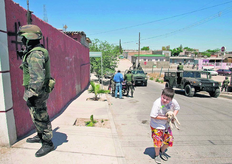 Un niño transita por una calle fuertemente custodiada en Chihuahua, estado donde han ocurrido varios crímenes contra menores. (Foto Prensa Libre: AFP)
