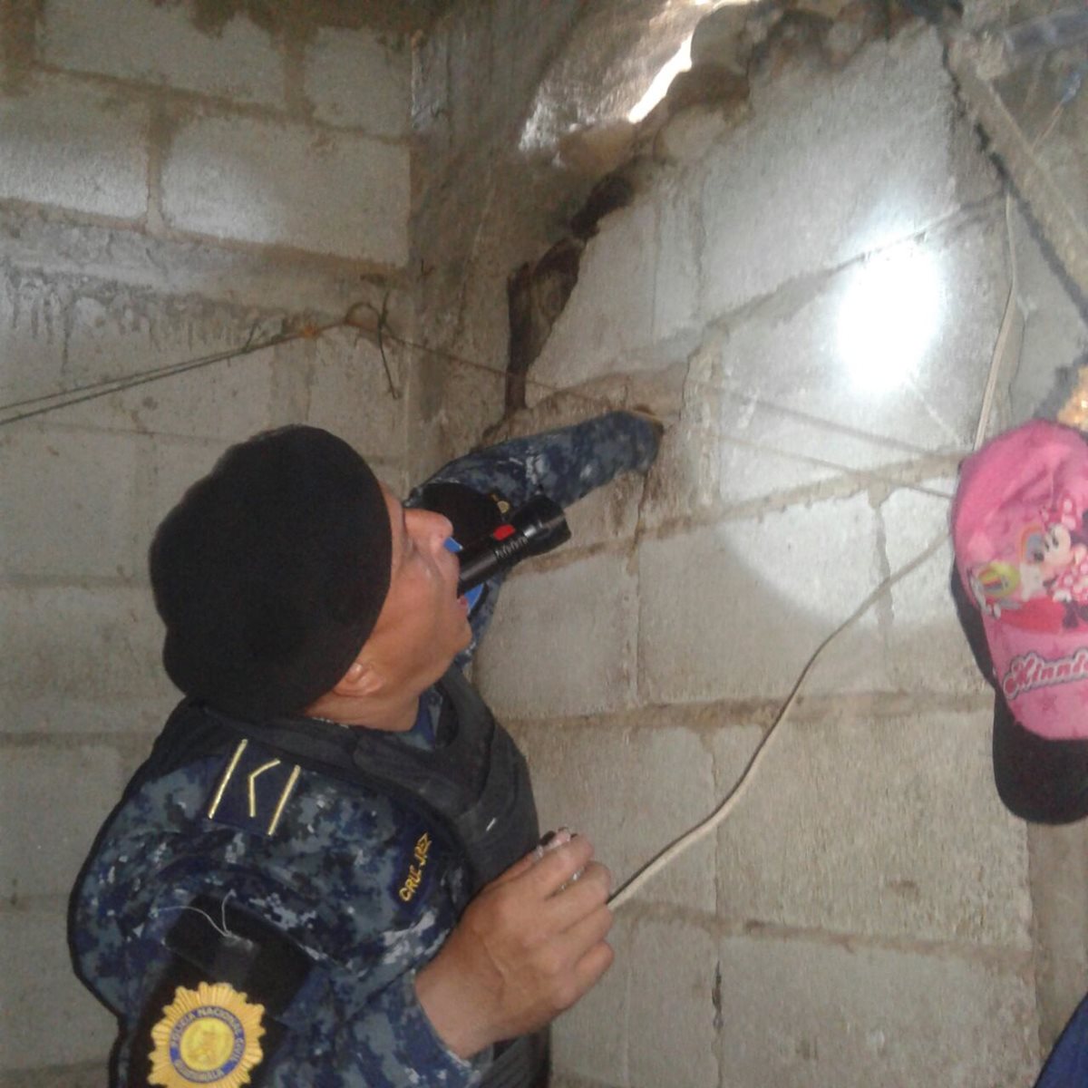 Un agente de la PNC extrae bolsas con marihuana escondidas en una vivienda allanada.(Foto Prensa Libre:PNC)