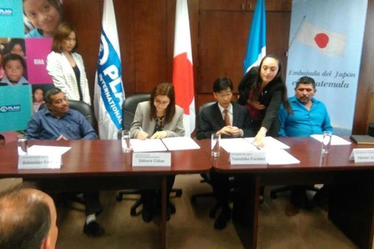 Débora Cóbar, directora de Plan Internacional, y Tomohiko Furutani, embajador del Japón, -al centro- firman convenio de cooperación. (Foto Prensa Libre).