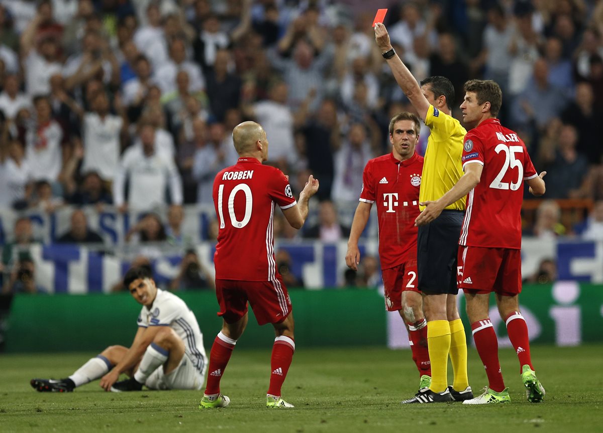El árbitro Viktor Kassai recibe reclamos de los jugadores del Bayern Múnich ante la expulsión de Arturo Vidal. (Foto Prensa Libre: AFP)
