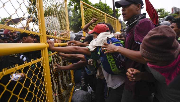 Momento en que las autoridades guatemaltecas intentan evitar el paso de hondureños hacia el puente internacional que divide el país con México. (Foto Prensa Libre: AFP)