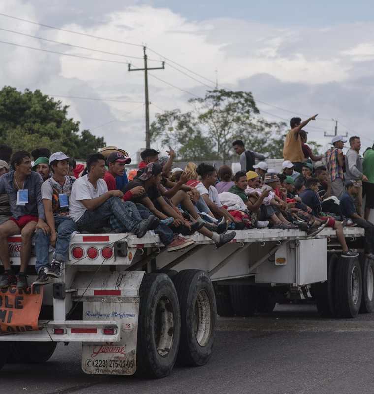 Migrantes aprovechan una plataforma jalada por un tráiler en Veracruz por el municipio de Sayula de Alemán. (Foto Prensa Libre: EFE)