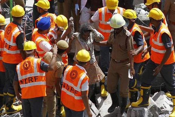 Bomberos asisten a superviviente del derrumbe de  edificio a las afueras de Chennai, India. (Foto Prensa Libre: AFP).