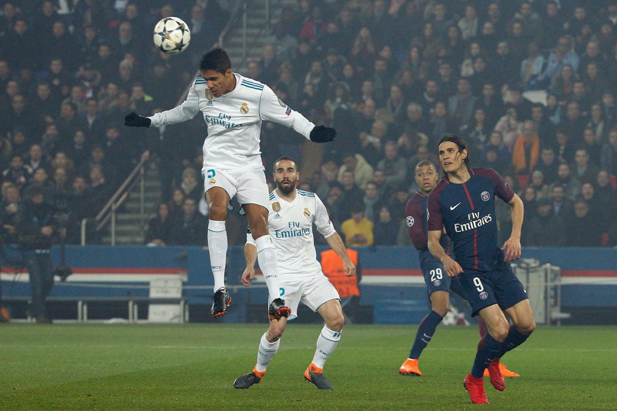 Raphael Varane salta y rechaza de cabeza un centro en el área del Real Madrid.