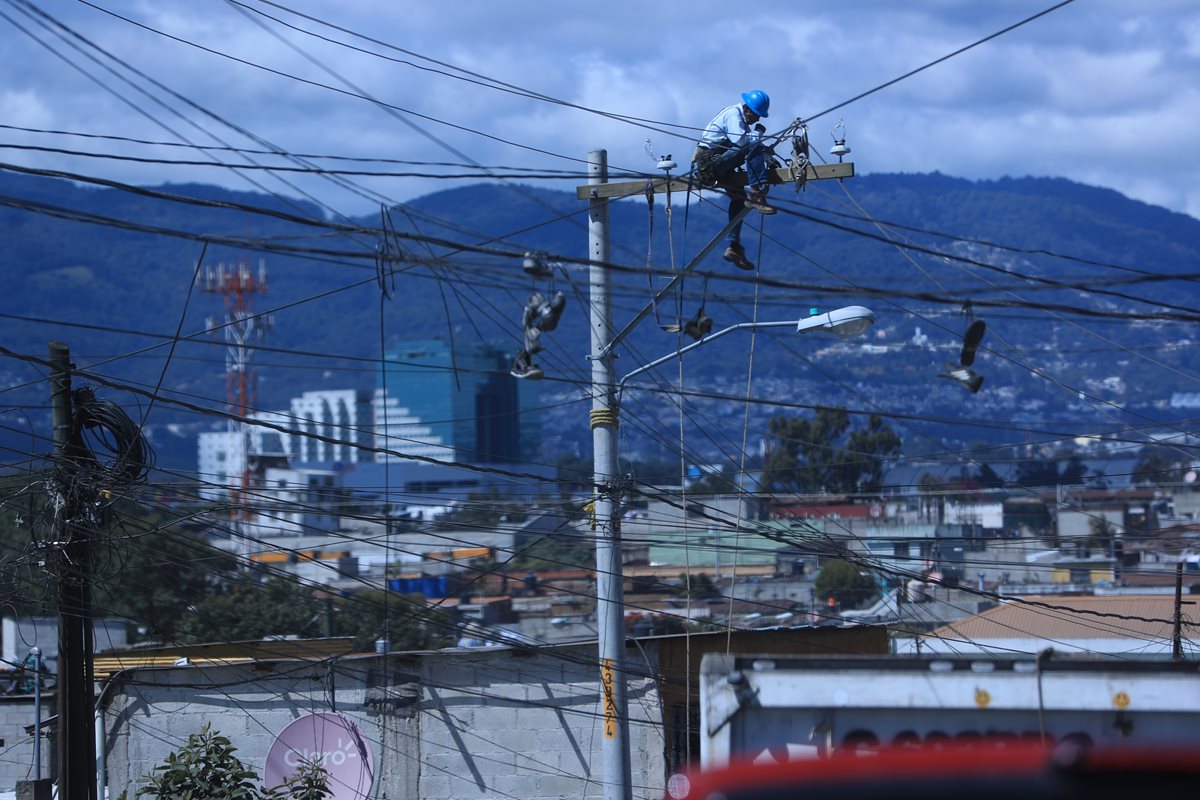 Electricistas de la Empresa Eléctrica de Guatemala, S.A., reparan la red que fue destruida por le incendio. (Foto Prensa Libre: Carlos Hernández)