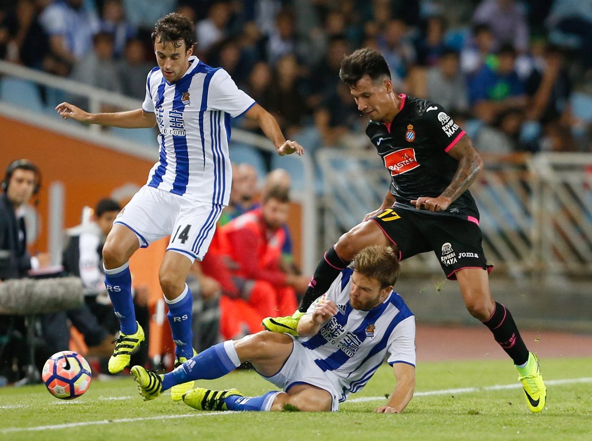 Los jugadores de la Real Sociedad Pardo (izquierda), e Illarra (abajo) luchan un balón con Hernan Pérez, del Espanyol. (Foto Prensa Libre: EFE)