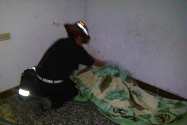 El cadáver del hombre supuestamente asesinado por su hijo, es cubierto por un Bombero Municipal. (Foto Prensa Libre: CBM)<br _mce_bogus="1"/>