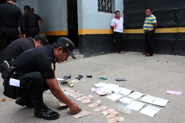 Policías cuentan el dinero decomisado. Al fondo, los dos hombres detenidos.