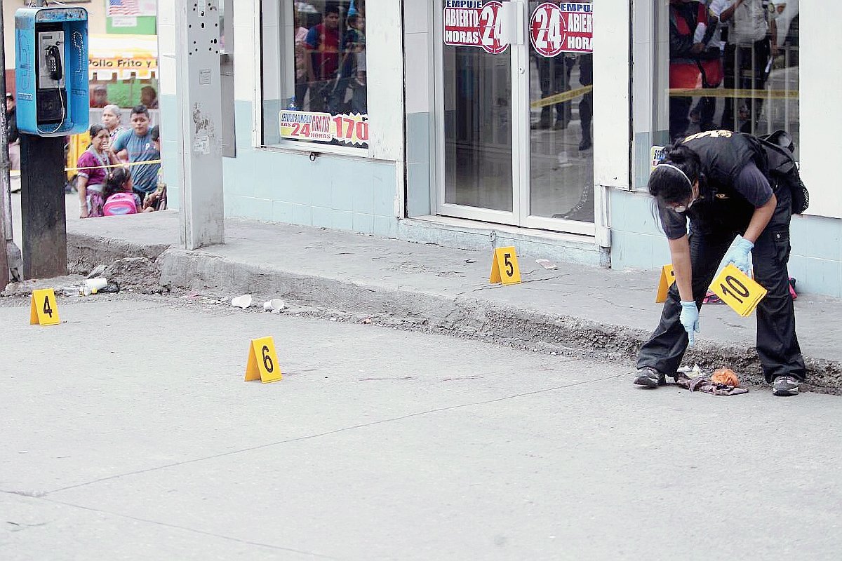 Peritos del Ministerio Públic recogen casquillos de bala en el lugar en el que fueron baleados los ayudantes de buses. (Foto Prensa Libre: Erick Ávila)