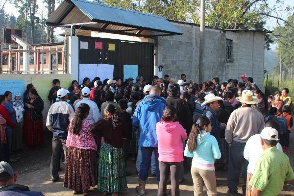 Padres de familia se reúnen frente a escuela.