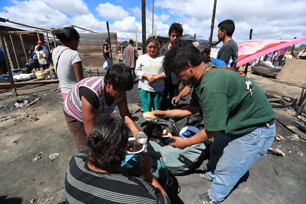 Miembros de una iglesia evangélica entregan alimentos a las familias damnificadas del asentamiento Los Pinos, en la zona 3.(Foto Prensa Libre: Carlos Hernández)