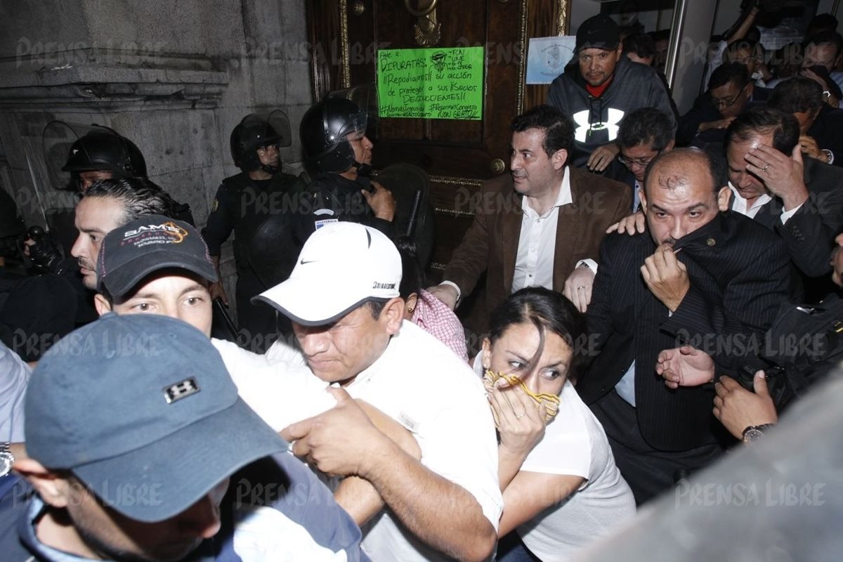 Diputados abandonan el Congreso de la República con el rostro cubierto. (Foto Prensa Libre: Paulo Raqueq)