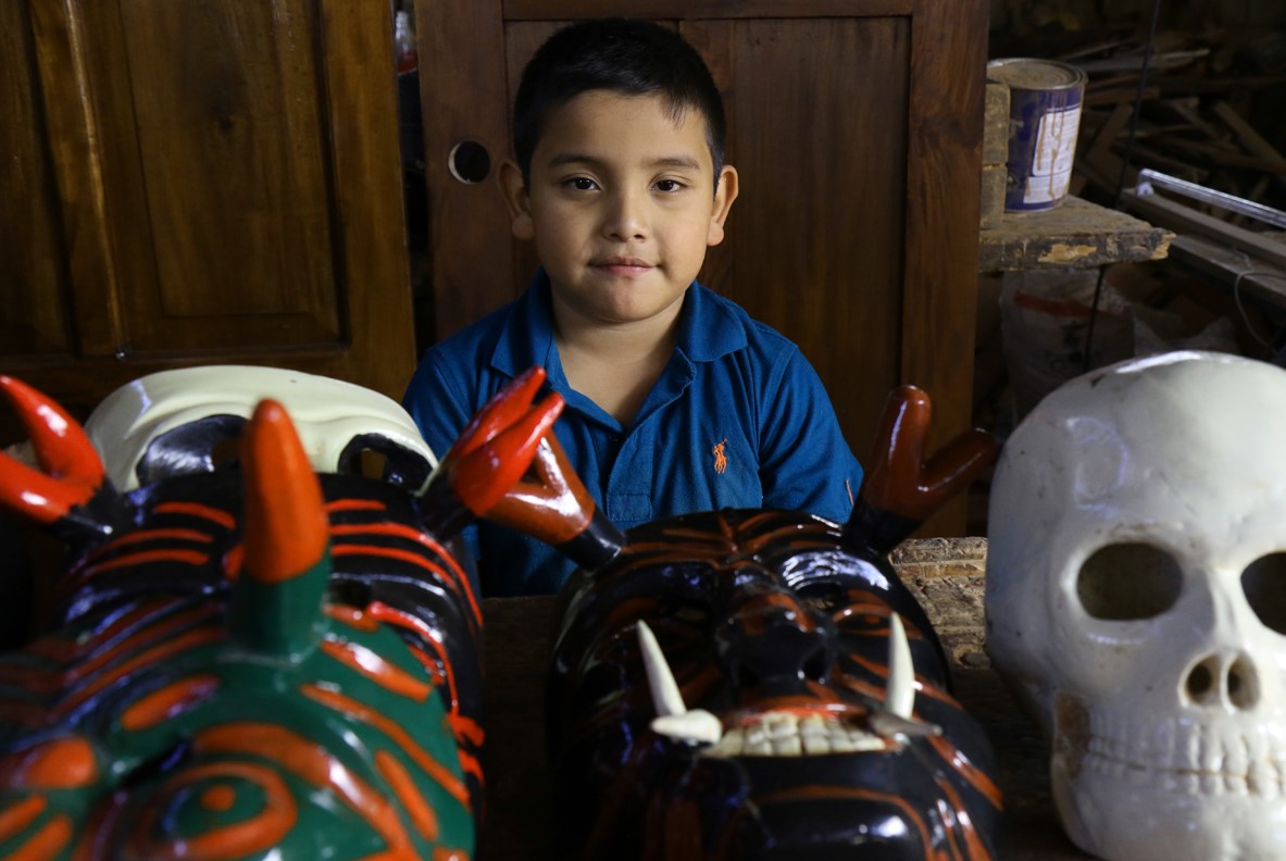 El pequeño Jordi Jesús ayuda en la elaboración de máscaras en el taller de la familia Hernández. (Foto Prensa Libre: Cortesía Victorino Tejaxún)