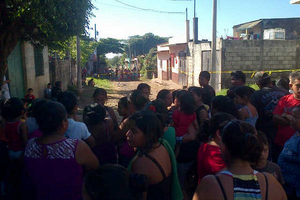 Vecinos observan las labores de la PNC fuera de la casa donde ocurrió el ataque. (Foto Prensa Libre: Enrique Paredes)