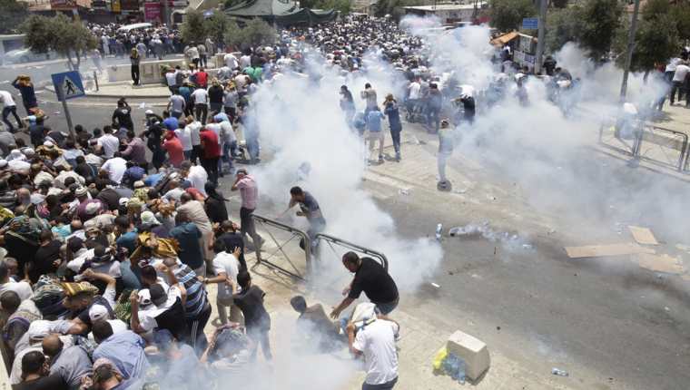 Los palestinos huyen de los gases lacrimógenos lanzados por la policía israelí fuera de la Ciudad Vieja de Jerusalén.(AP).