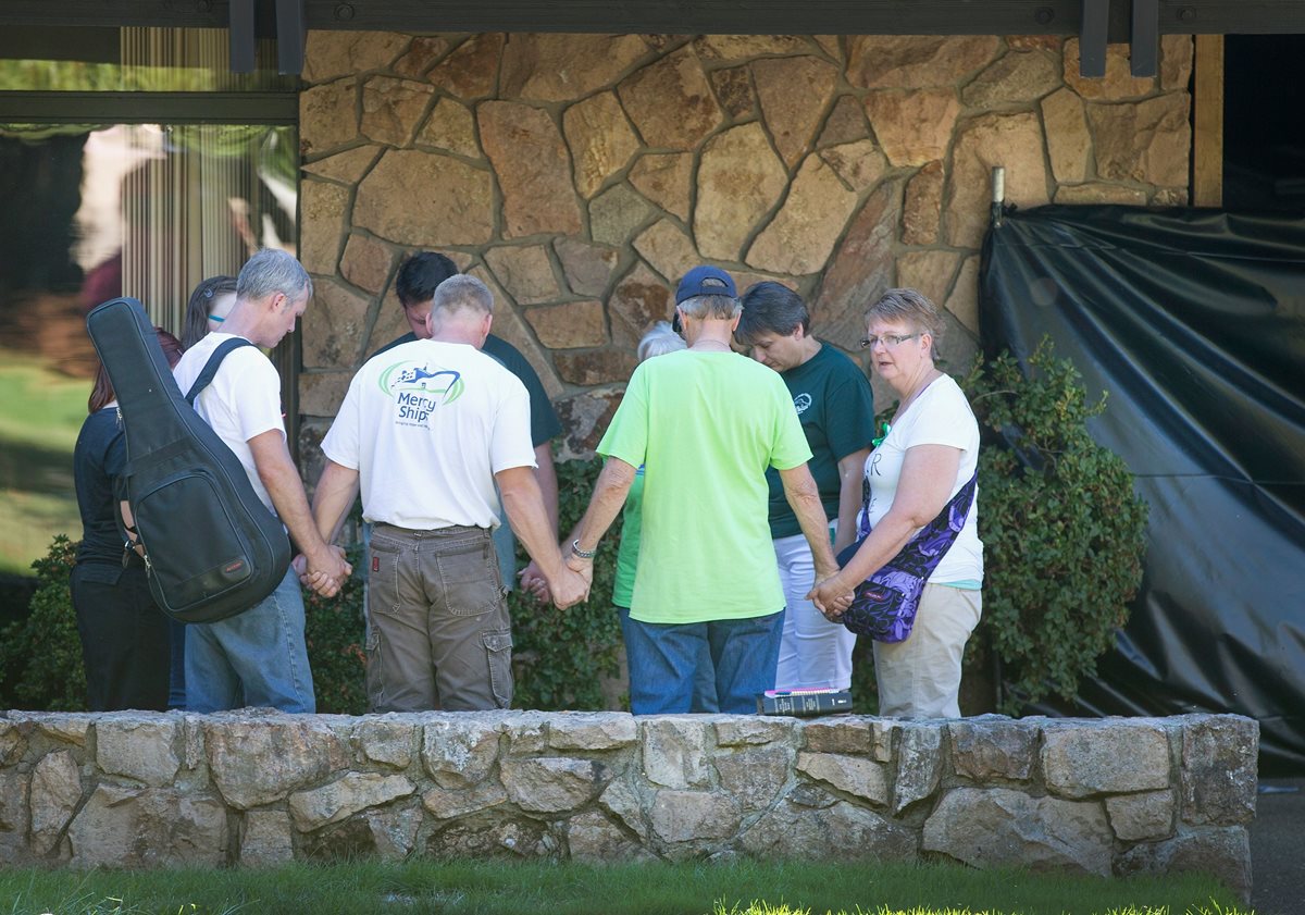Personas hacen una oración previo al inicio de actividades en el colegio comunitario de Rosebur donde ocurrió la masacre la semana pasada. (Foto Prensa Libre: AFP).