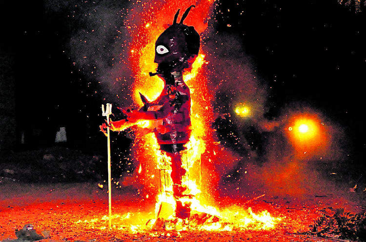 Vecinos del barrio El Zapatillo, Chiquimula, observan la piñata de la imagen de Satanás que es consumida por las llamas.