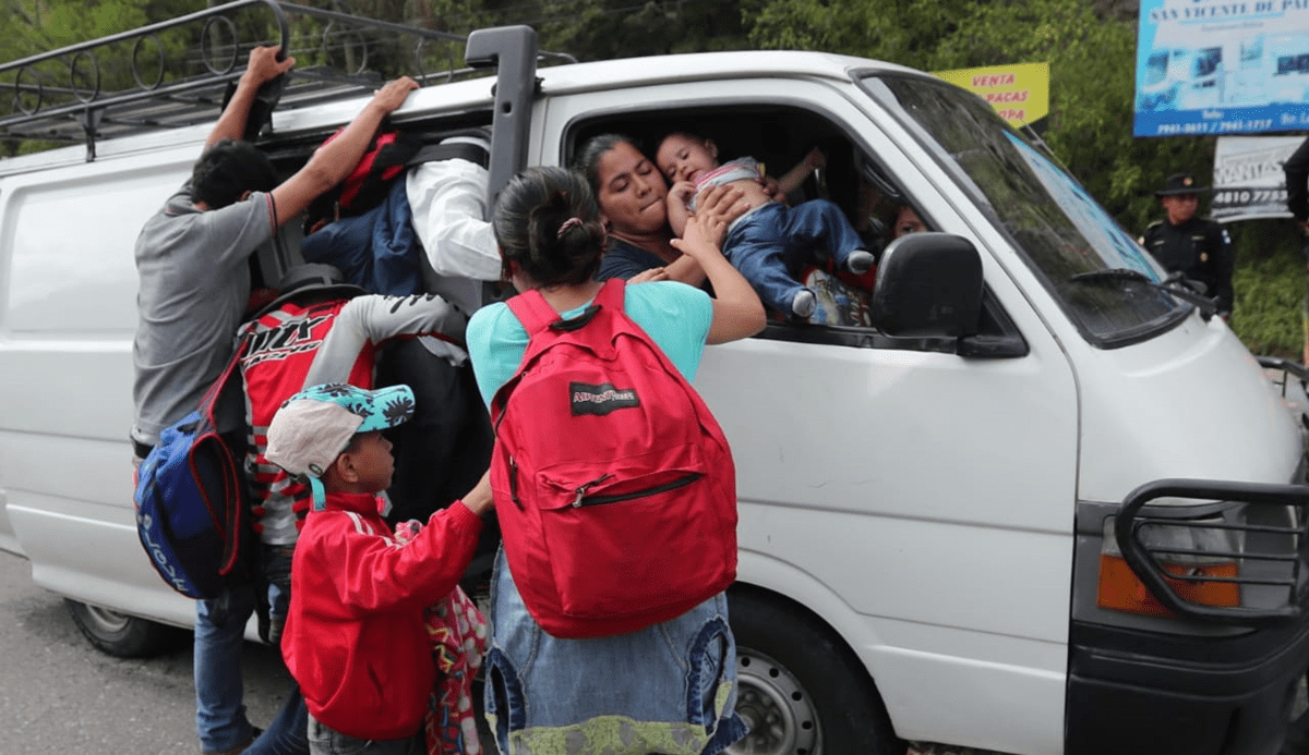 Una mujer le da su bebé a su hermana que logró abordar un microbús en Zacapa. (Foto Prensa Libre: Érick Ávila)