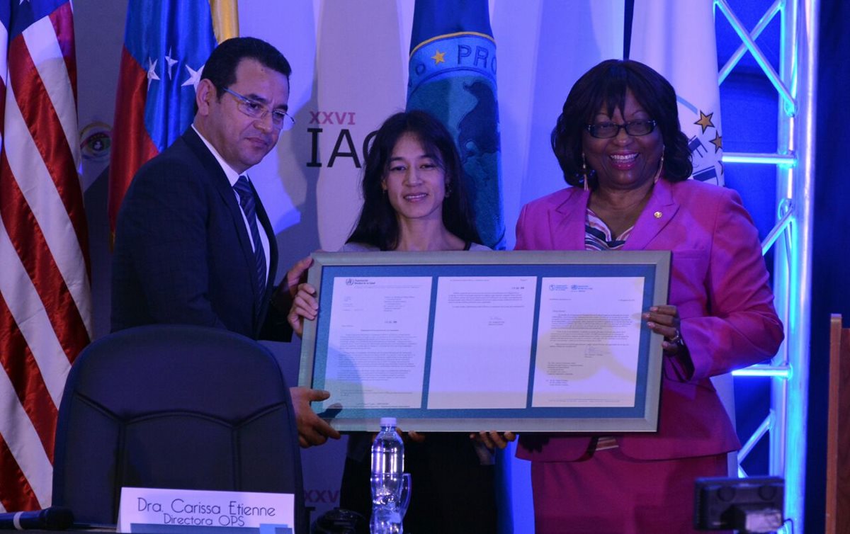 La directora de la OPS, Carissa Etienne, entrega la certificación de eliminación de oncocercosis a la ministra de Salud, Lucrecia Hernández y al presidente Jimmy Morales. (Foto Prensa Libre: Ministerio de Salud).