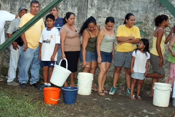 Pobladores hacen cola para abastecerse de agua en un chorro improvisado  colocado bajo la bomba de agua, en la colonia Bananera.
