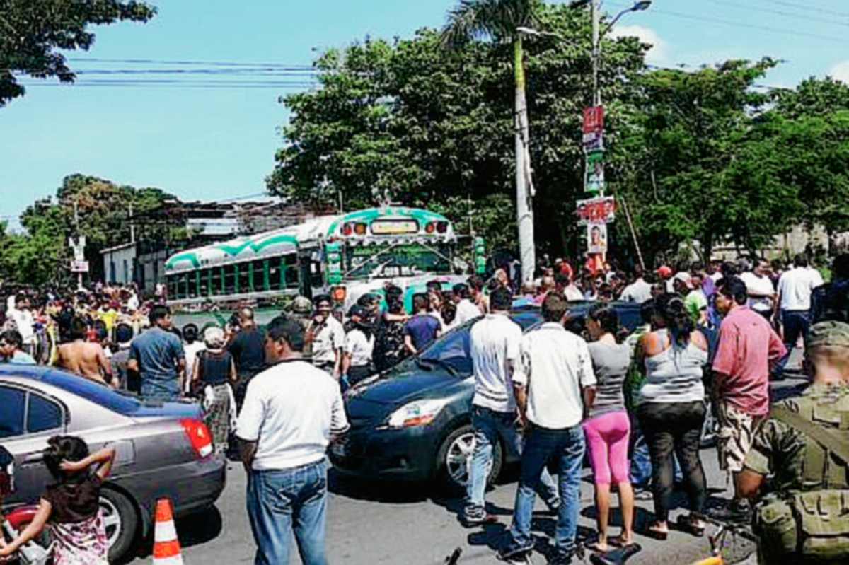 Vecinos de la zona 5 de la cabecera de Escuintla se acercan a la escena del crimen, donde un piloto de autobús murió baleado. (Foto Prensa Libre: Carlos Enrique Paredes)