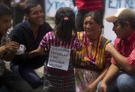Una niña sostiene un cartel con un mensaje contra la instalación de brigada militar en San Juan. (Foto Prensa Libre: EFE)