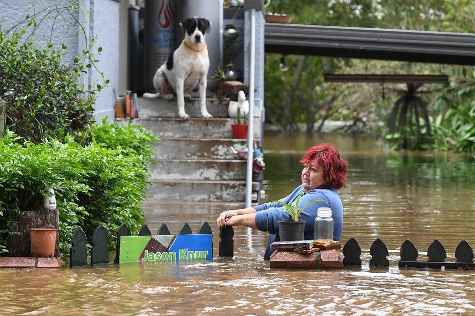 Una mujer intenta alcanzar su case mientras su perro la observa, en la región central de Lismore, Nuevo Gales Sur, Australia. Las autoridades temen que muchas personas se hayan ahogado tras la emergencia de inundaciones que azota dos estados por el paso del ciclón Debbie. Decenas de miles de residentes han sido evacuados en la zona norte de Nueva Gales Sur y el sur de Queensland. La tormenta ya salió al mar después de golpear el norte de Queensland como un ciclón de categoría cuatro, el martes. DAVE HUNT/EPA