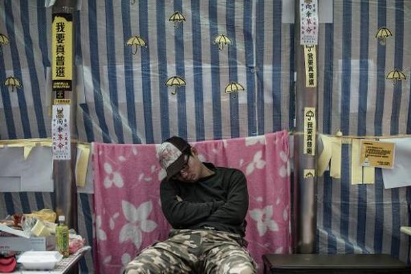 Un manifestante prodemocrático duerme en una silla en el distrito de Mongkok, Hong Kong. (Foto Prensa Libre: AFP)