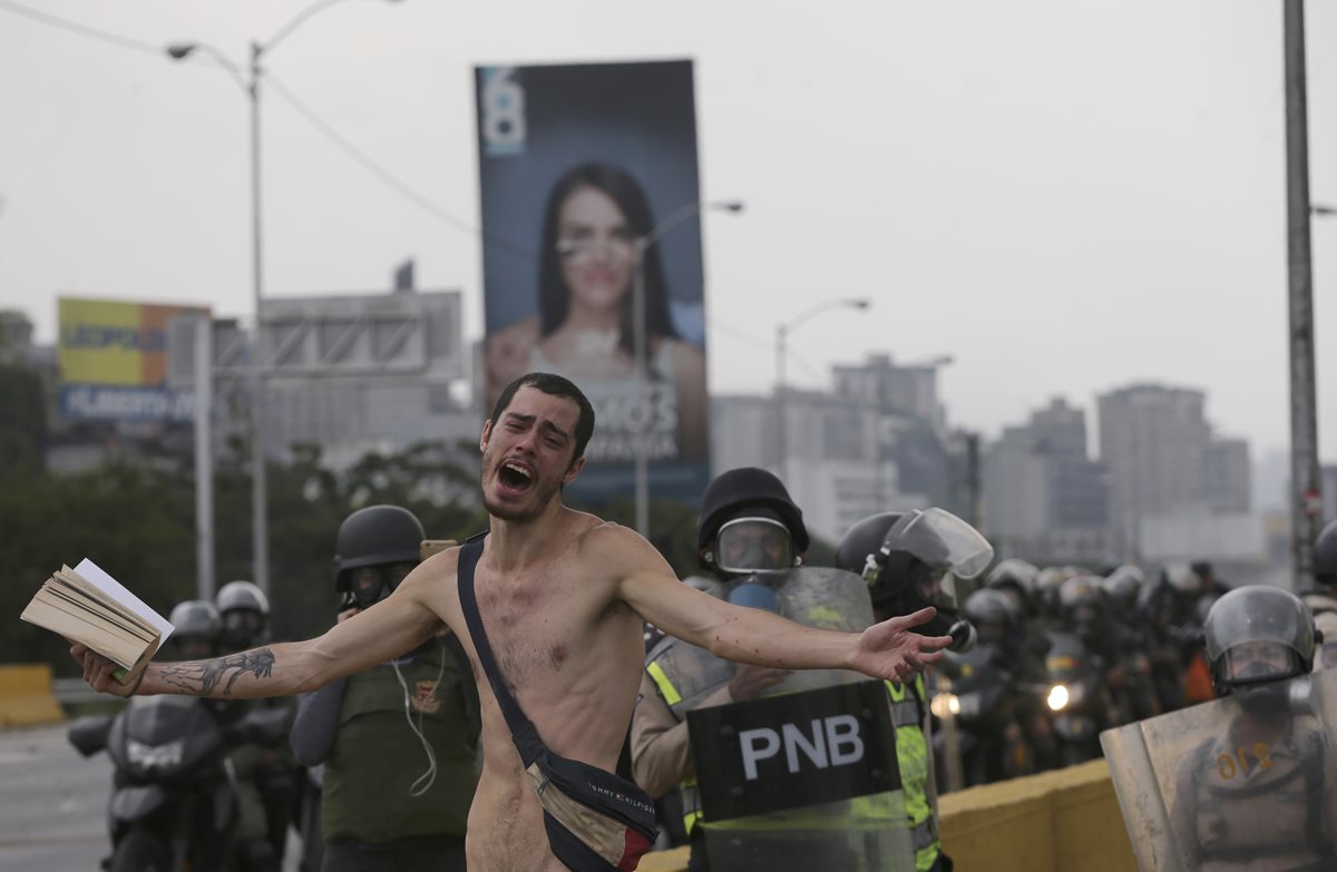 Momento en que manifestantes desnudo pedía frenar el lanzamiento de bombas en Caracas, Venezuela. (Foto Prensa Libre: AP)