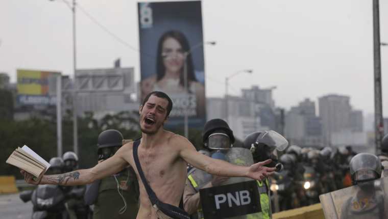 Momento en que manifestantes desnudo pedía frenar el lanzamiento de bombas en Caracas, Venezuela. (Foto Prensa Libre: AP)