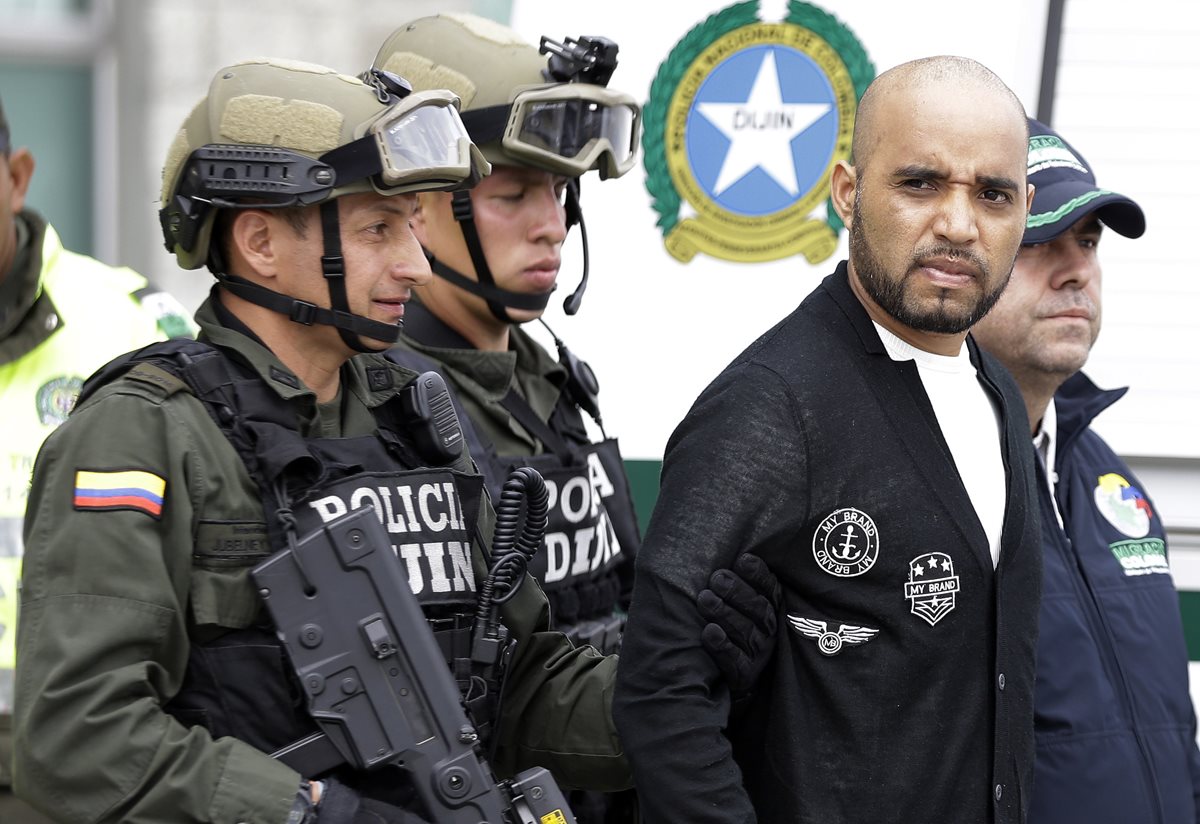 Gerson Gálvez (izquierda), es escoltado por miembros de seguridad colombianos previo a abordar el avión que lo llevó hasta Perú. (Foto Prensa Libre: AP).