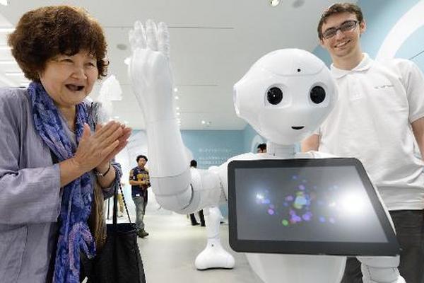 Una mujer saluda al robot Pepper, desarrollado por el grupo japonés   SoftBank y el fabricante francés Alderbaran. (Foto Prensa Libre: AFP)