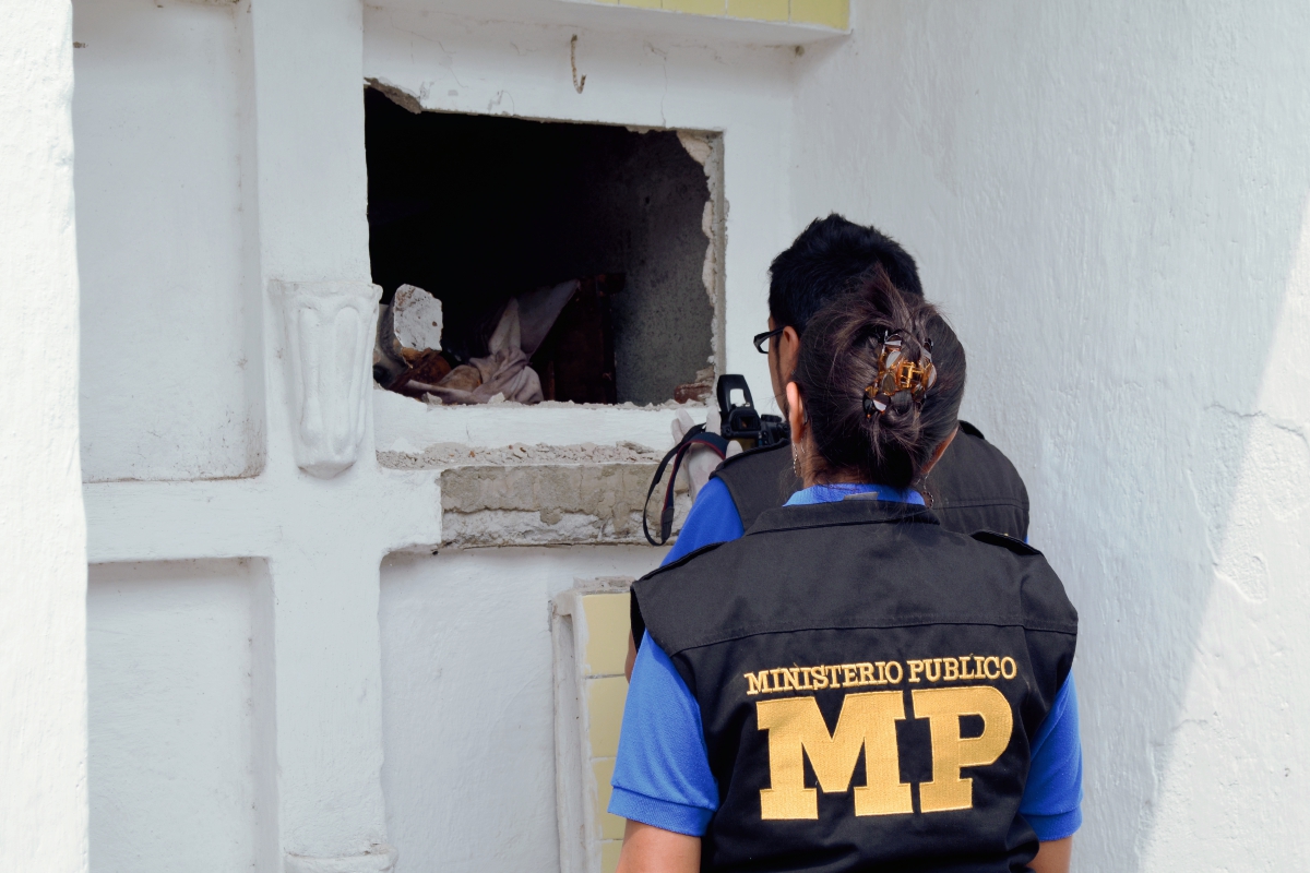 Fiscales del Ministerio Público inspeccionan la tumba profanada en el cementerio general de Retalhuleu. (Foto Prensa Libre: Jorge Tizol)