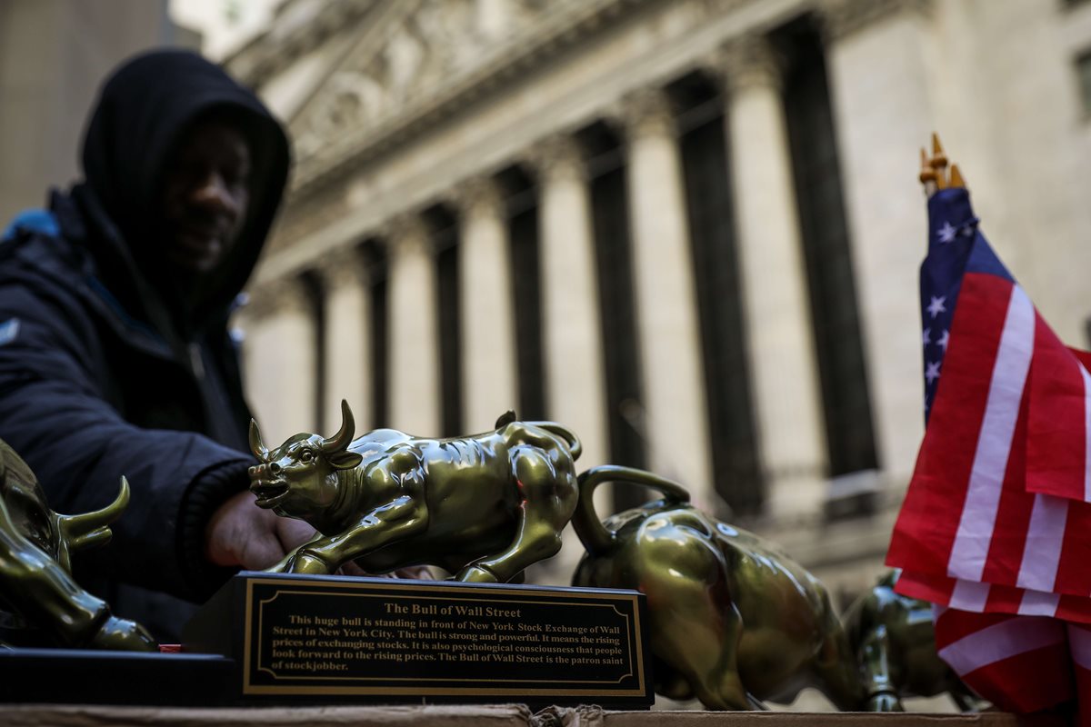 Un comerciante vende réplicas de los toros de Wall Street, sacudida por los escándalos de Facebook, en Nueva York. (Foto Prensa Libre: AFP)